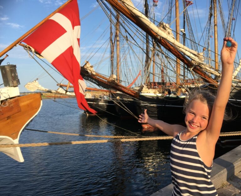 Een kind in een haven met de Deense vlag