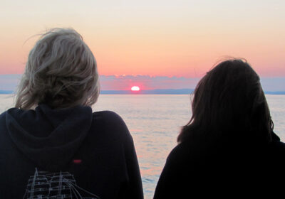 mensen-bekijken-zonsondergang Mensen bekijken de zonsondergang op zee