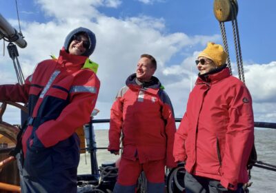 schipper-roer-nil-desperandum De schipper van de Nil Desperandum staat vrolijk aan het roer. Naast hem staan 2 gasten