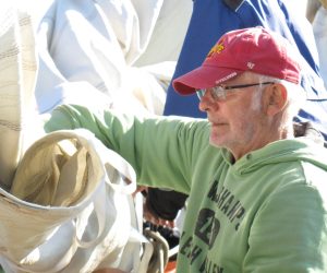 Een man doekt een zeil op